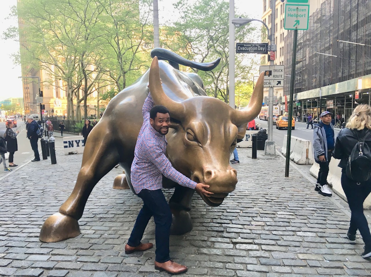 Osasere Ehigie beside the Charging Bull sculpture in New York City